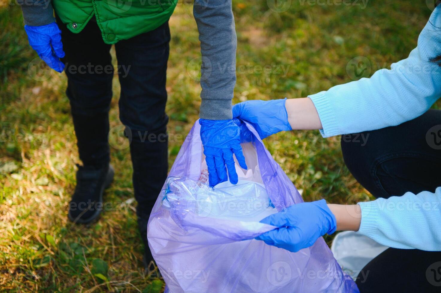 mamma lär henne son till rena upp skräp i natur. en kvinna tar bort plast flaskor i en väska. de ämne av miljö- förorening förbi sopor. foto