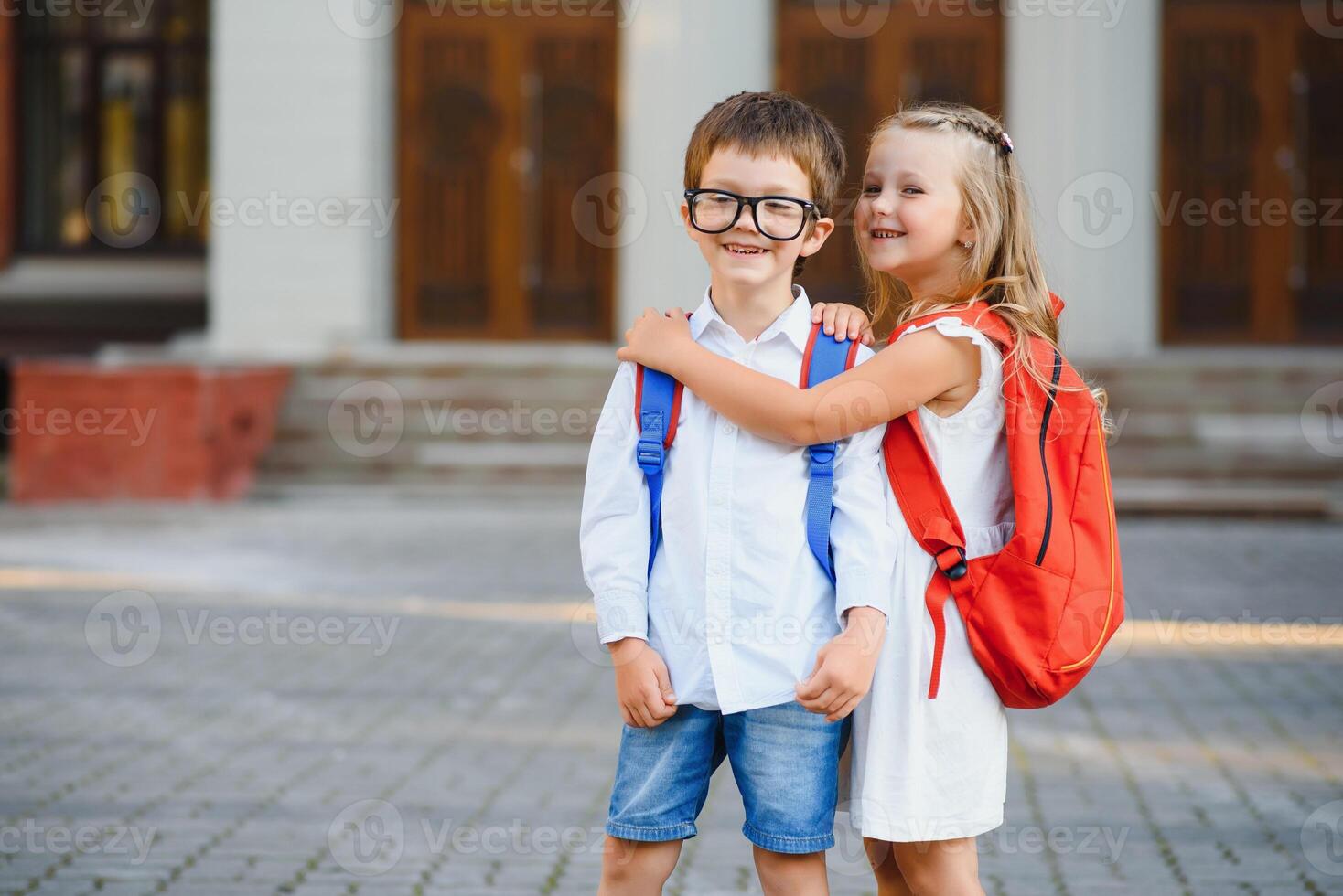 Lycklig barn - pojke och flicka med böcker och ryggsäckar på de först skola dag. upphetsad till vara tillbaka till skola efter semester. full längd utomhus- porträtt. foto