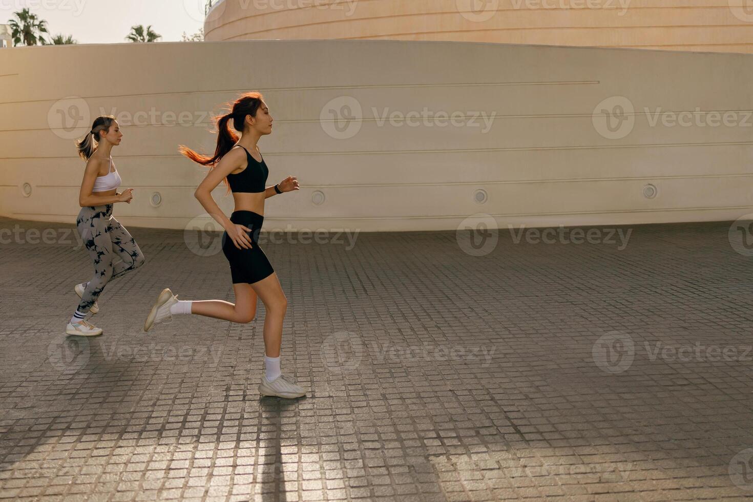 två atletisk kvinnor i sportkläder är joggning runt om de stad i tidigt morgon. nå de mål foto