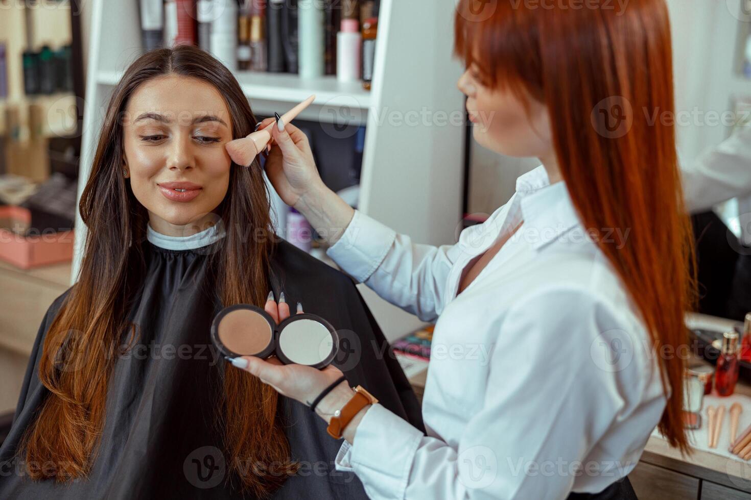 professionell smink konstnär applicering bronzer pulver med en borsta i skönhet salong foto