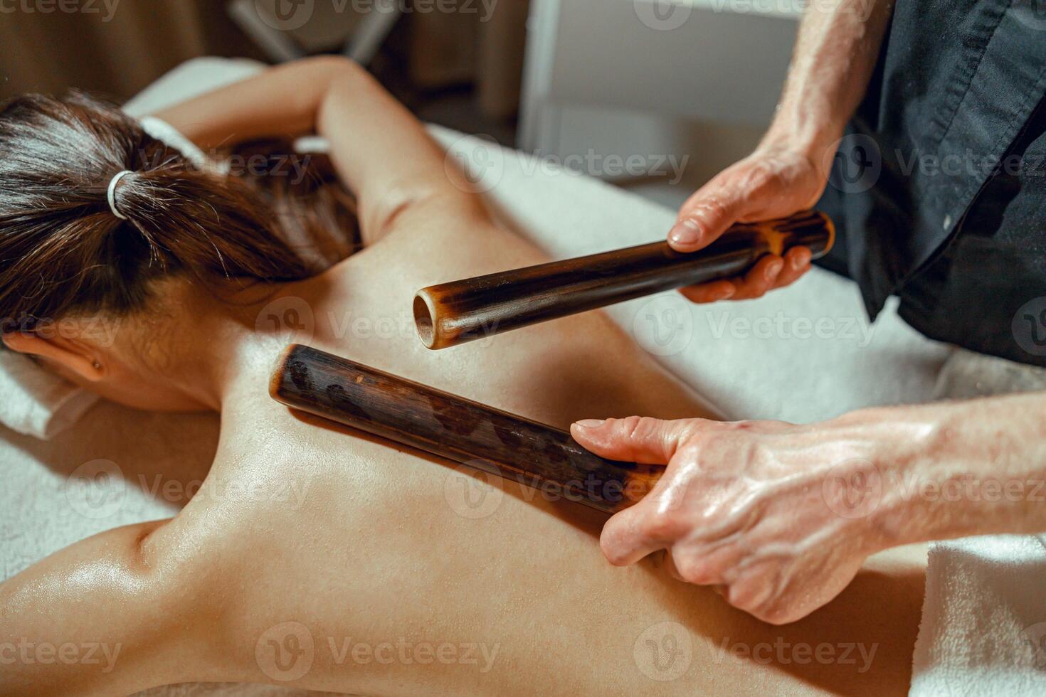 närbild manlig händer håller på med tillbaka massage till kvinna använder sig av ihålig bambu käppar foto