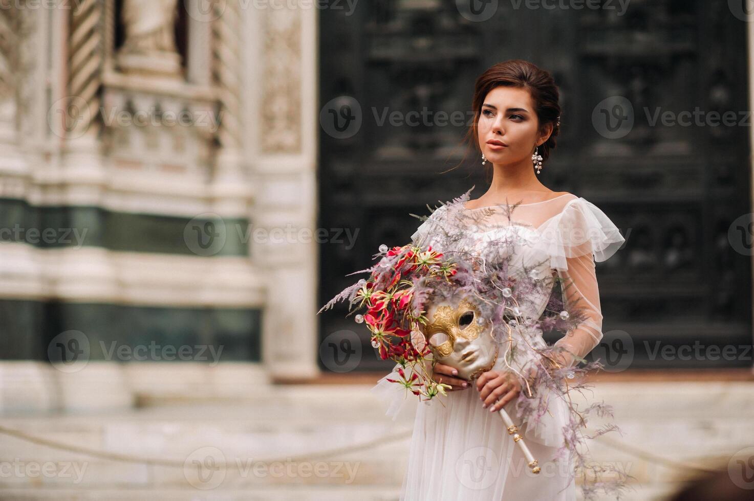 de flicka-brud är med skön blomma mönster som en mask i Florens, eleganta brud i en bröllop klänning stående med en mask i de gammal stad av florens. modell flicka i florens foto