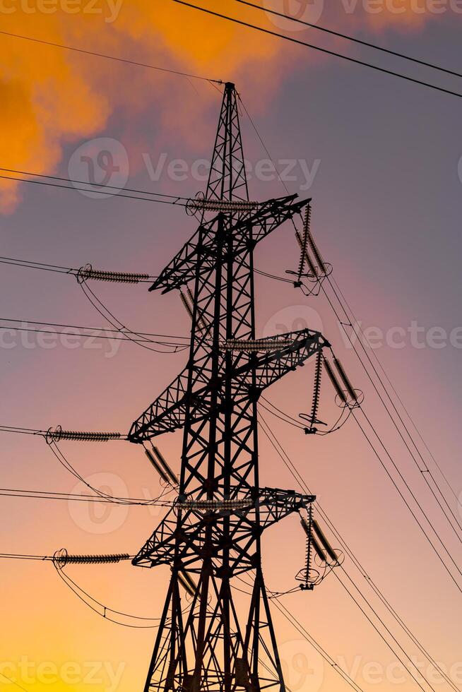 metall elektrisk pelare med orange himmel bakgrund. kraft överföring anläggningar. hög Spänning pyloner mot solnedgång bakgrund. energi och industrialisering begrepp. selektiv fokus foto