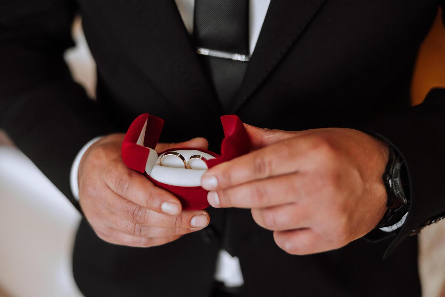 de ung brudgum innehar bröllop ringar i hans hand. de man innehar två guld bröllop ringar i hans hand. bröllop ceremoni. foto