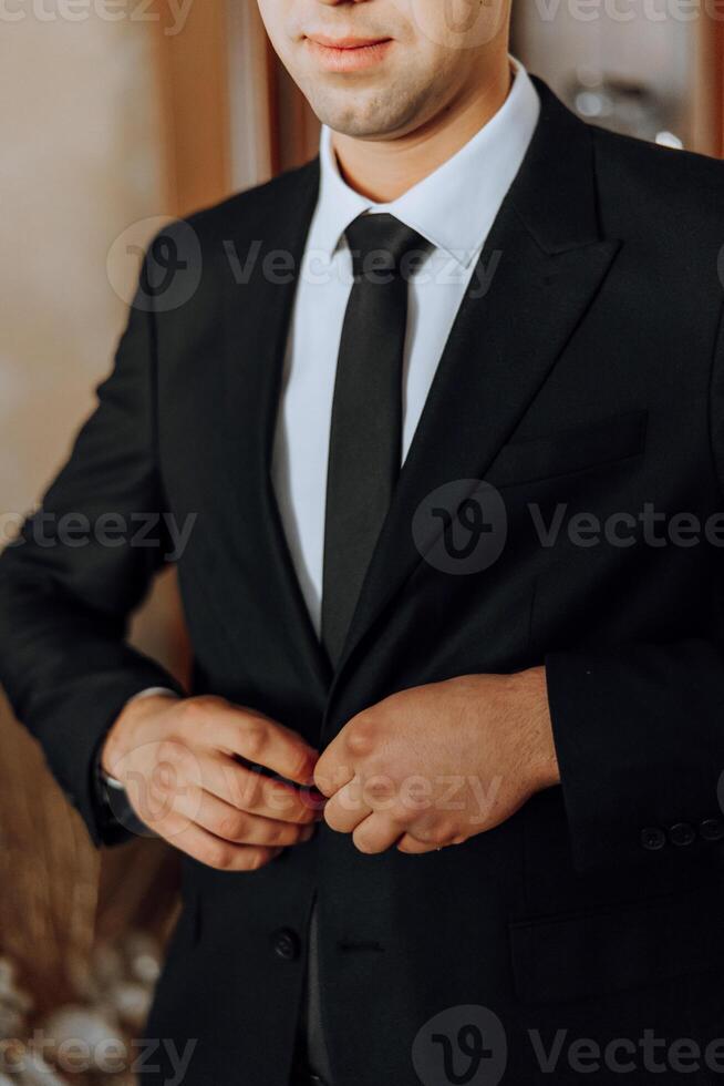 de brudgummens händer fästa hans jacka i de morgon- innan de bröllop. närbild av en man i företag kostym. affärsman sätter på en kostym. de man fäster de knappar på hans jacka. foto