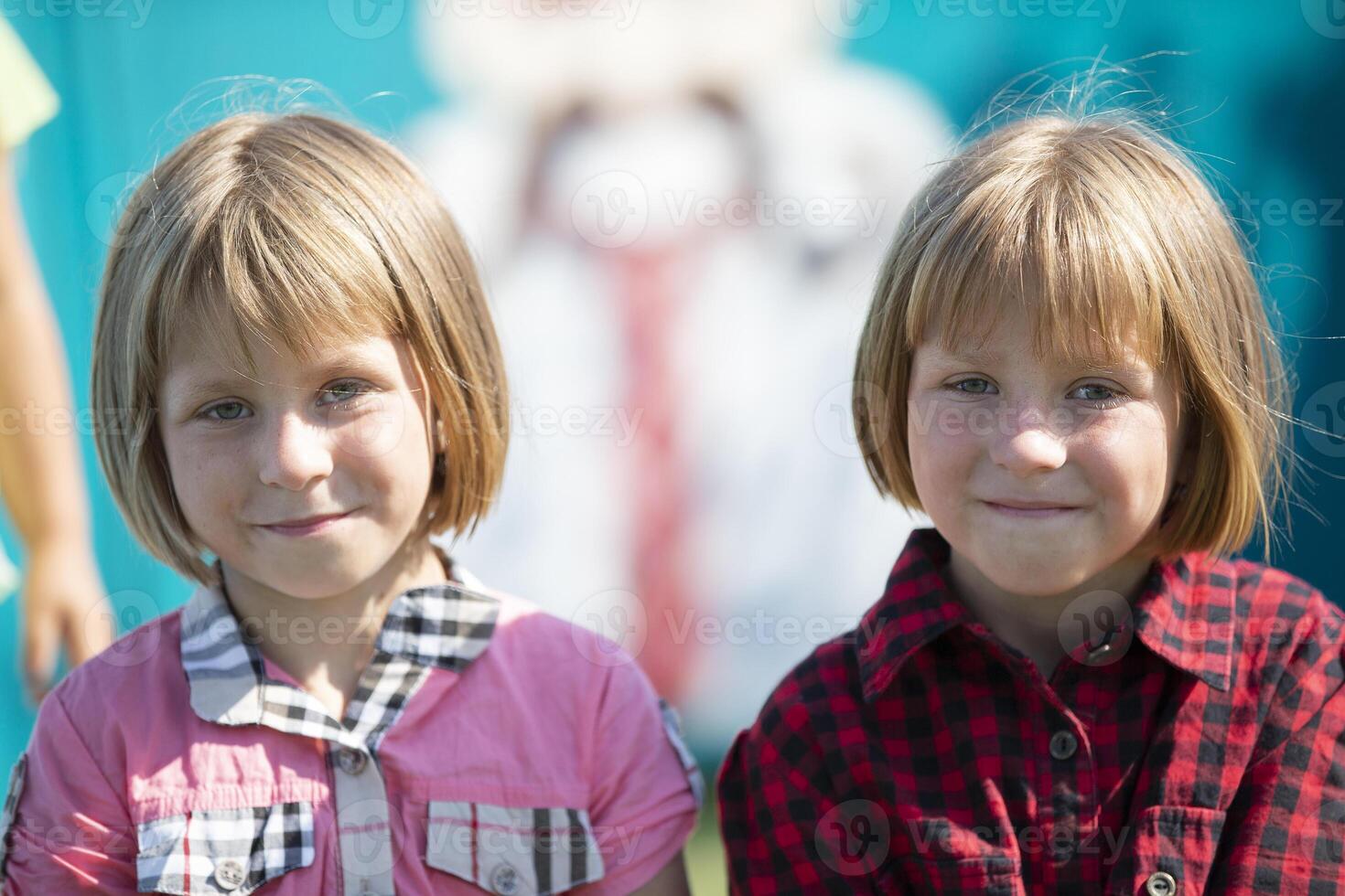 liten flickor tvilling systrar se på de kamera och leende. foto