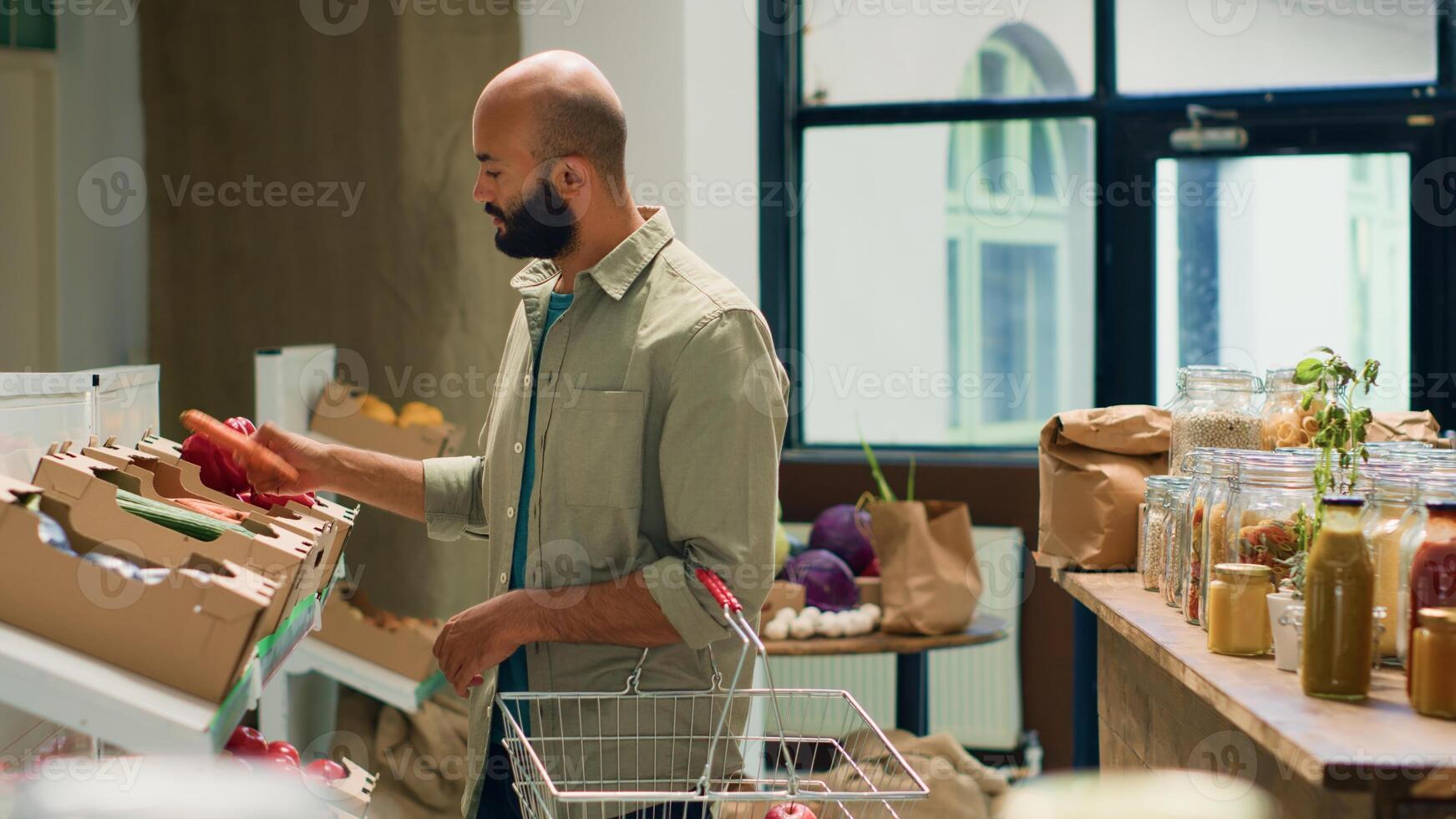 kund ser på bio gurkor i lådor, uppköp organisk nyligen UPPTAGITS grönsaker till laga mat friska vegan måltid. ung klient i lokal- eco vänlig mataffär, kemikalier fri mat. foto