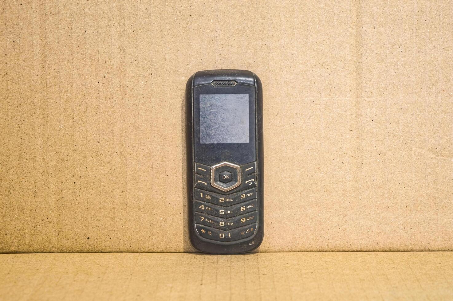 gammal mobiltelefon med en enkel brun bakgrund foto