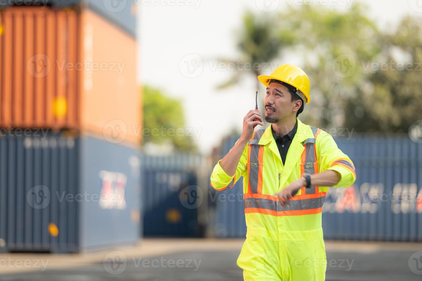 arbetare i de importera och exportera industri använda sig av walkie talkies till kommunicera med drivrutiner av nå stacker behållare i ett tömma behållare lager. foto