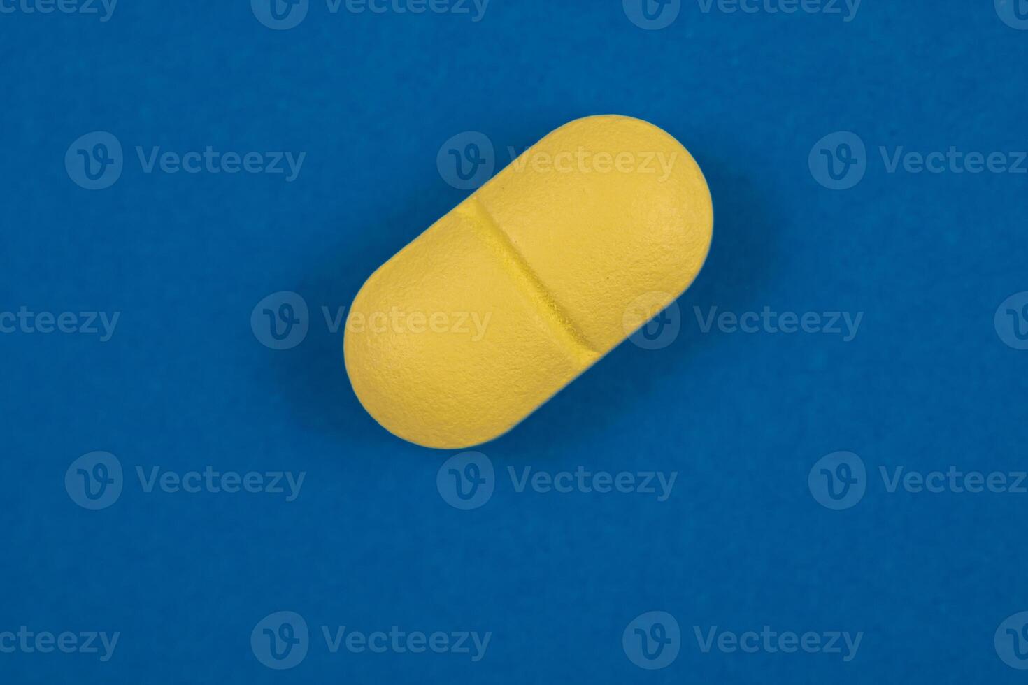 oval formad gul piller i makro se isolerat på blå bakgrund foto