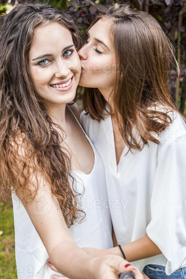 två kvinna ung vänner ta en selfie kramade tillsammans foto