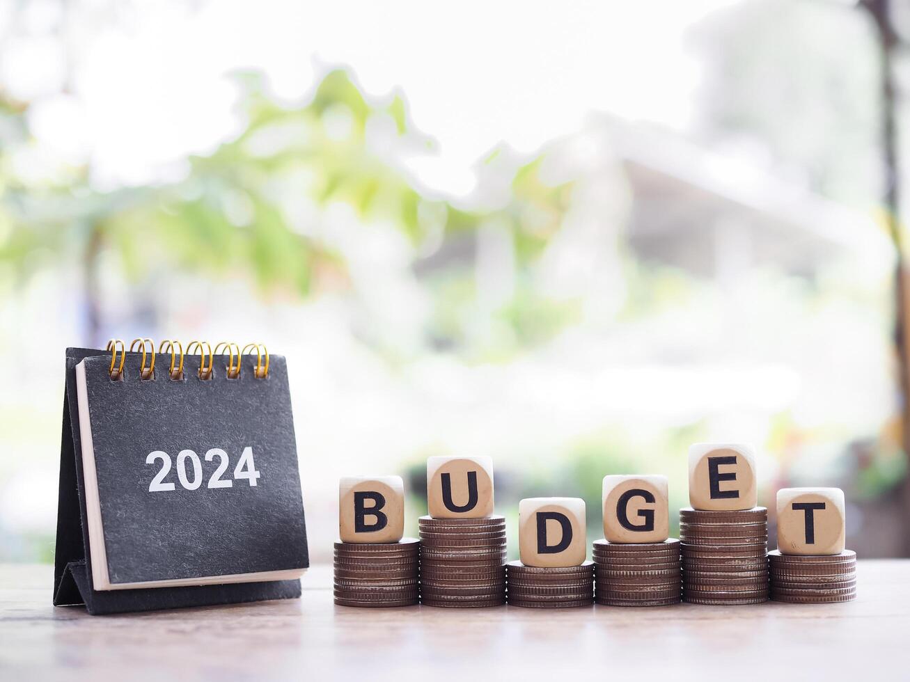 2024 skrivbord kalender, trä- block med de ord budget på stack av mynt. de begrepp handla om budget planera och tilldelning i år 2024 foto