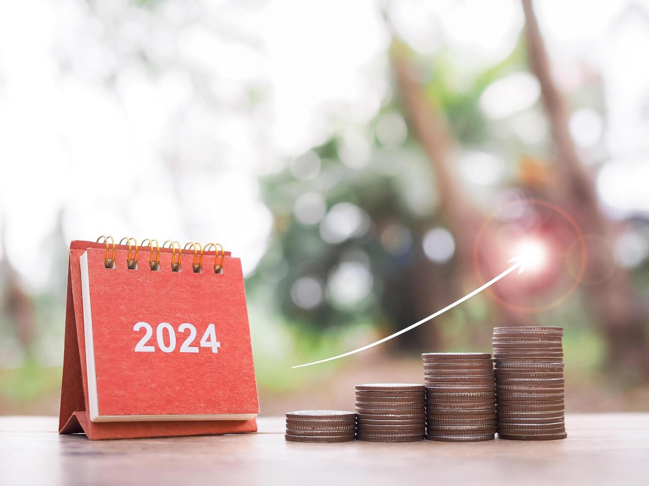 2024 skrivbord kalender, stack av mynt med pil stigande och mål ikoner. de begrepp av företag tillväxt, finansiell investering, marknadsföra stock, vinst lämna tillbaka, utdelning och företag fond i år 2024 foto