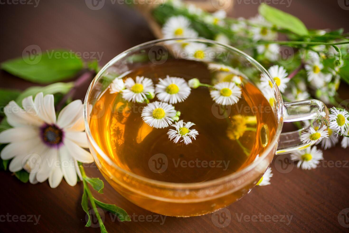 kamomill blomma te i en glas kopp och tekanna, på en trä- tabell. foto