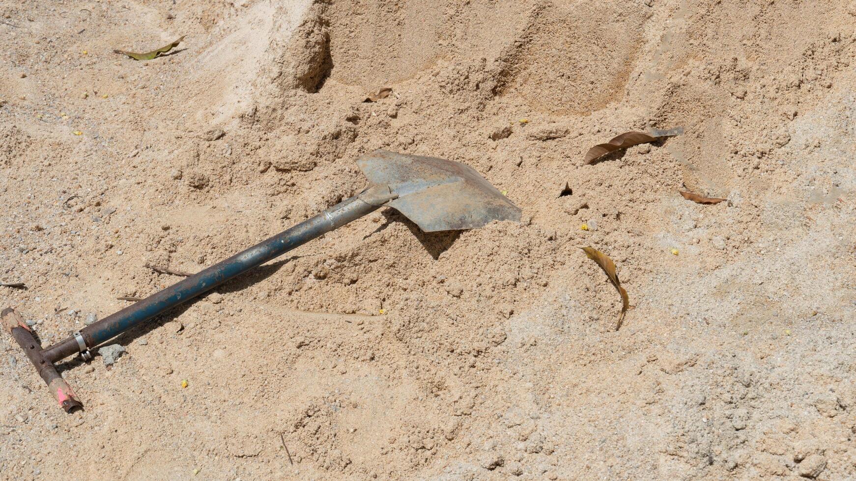 konstruktion bakgrund. stål av skyffel är stödd upp på en lugg av sand. utomhus i de Sol. foto