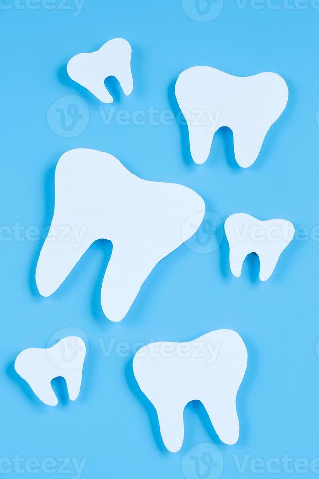 papper skära attrapp av tand på blå bakgrund. dental vård begrepp. internationell tandläkare dag. foto