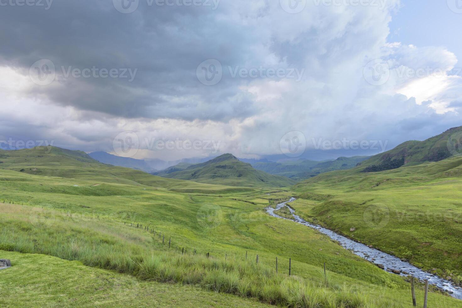 regn på de berg och de flod strömmande i en grön dal foto