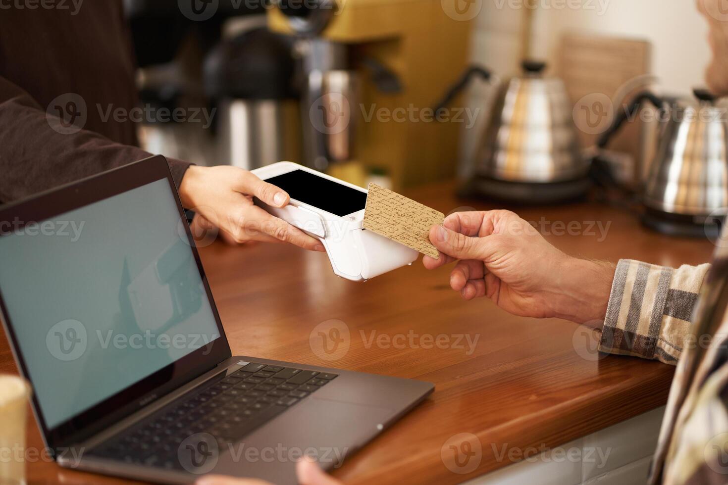 beskurna skott av manlig hand betalande kontaktlös för hans beställa i kaffe affär, Sammanträde på disken med bärbar dator, brådskande kort till pos terminal, arbetssätt från Hem foto