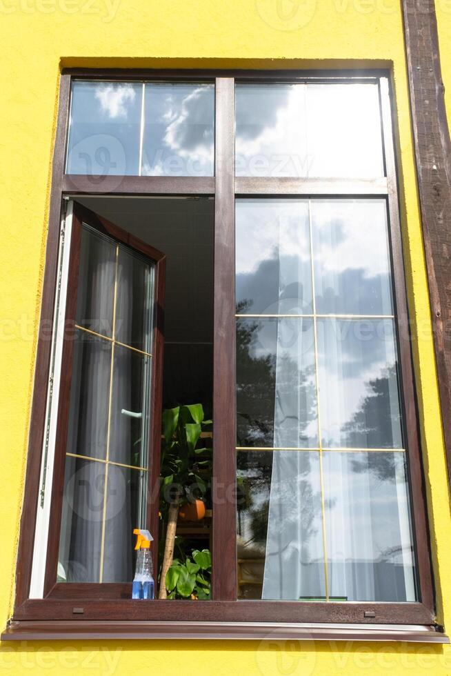 en fönster rengöring spray, en trasa och en mopp stå på de fönster tröskel av ett öppen fönster utanför för vår allmän rengöring foto