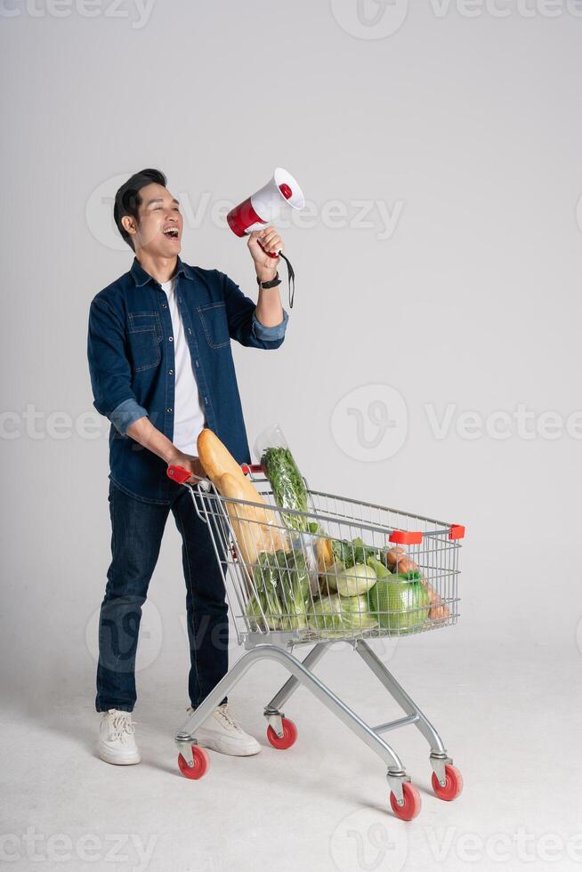 Lycklig leende man tryckande mataffär vagn isolerat på vit bakgrund foto