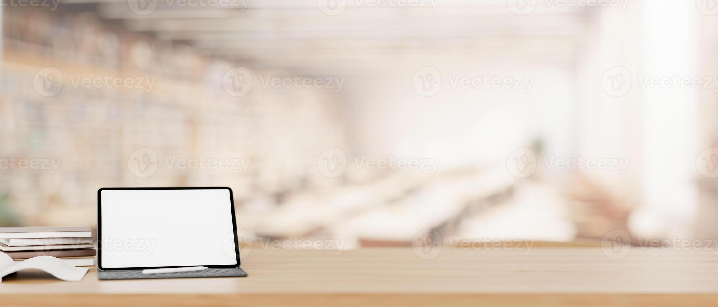 en vit skärm digital läsplatta attrapp på en trä- tabell i en samtida rymlig bibliotek. foto