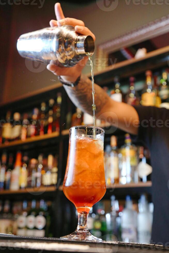 bartender häller en cocktail in i en stammade glas foto