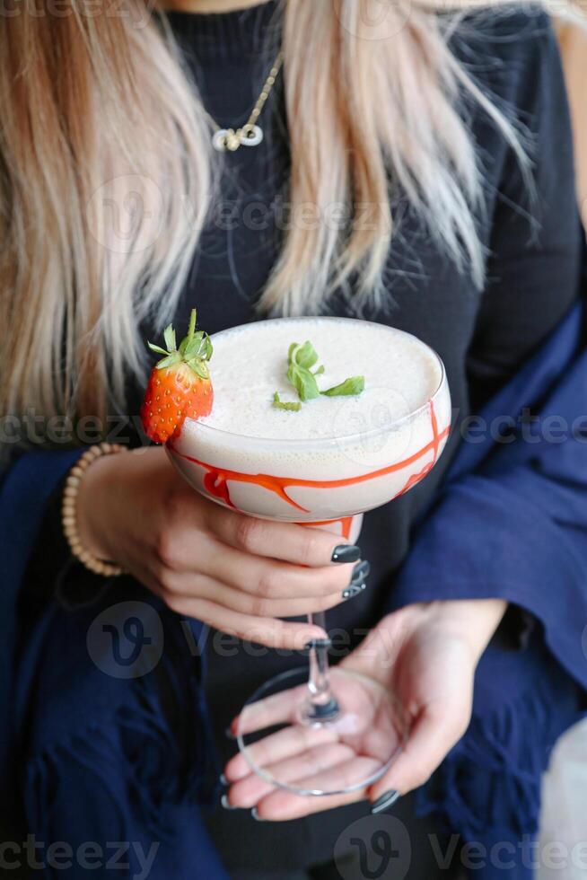 kvinna innehav Martini glas med jordgubb garnering foto