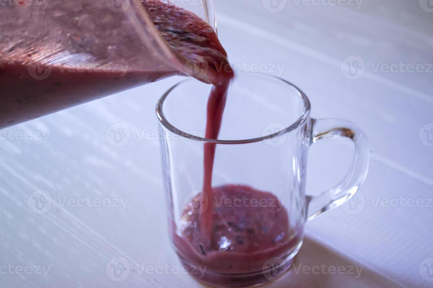 häller frukt smoothie i de glas kopp. foto