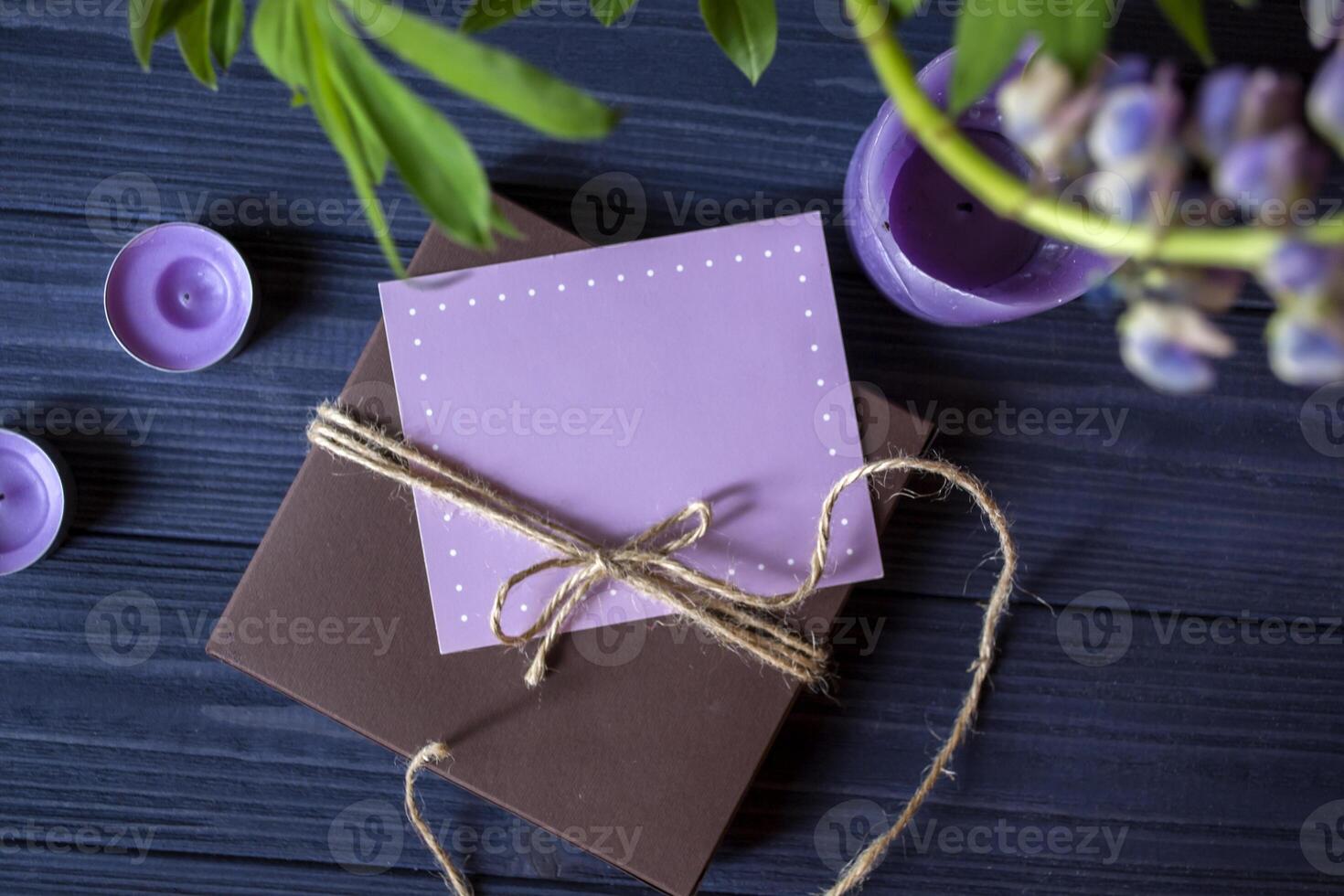 gåva låda med hälsning kort och bukett av lupiner på en mörk blå trä- bakgrund. foto