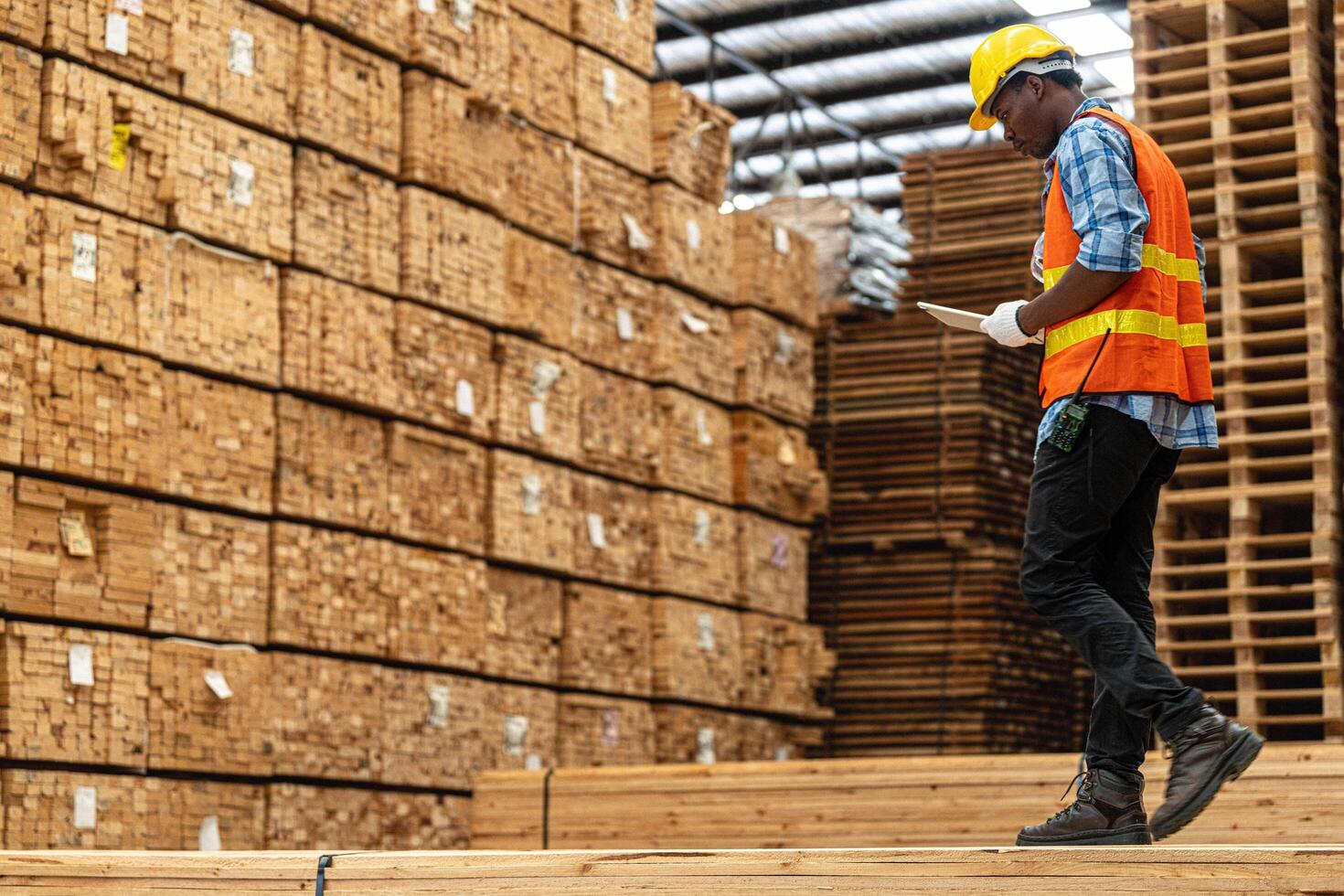 afrikansk arbetare man teknik gående och inspekterande med arbetssätt svit klänning och hand handske i timmer trä lager. begrepp av smart industri arbetstagare fungerar. trä fabriker producera trä gom. foto