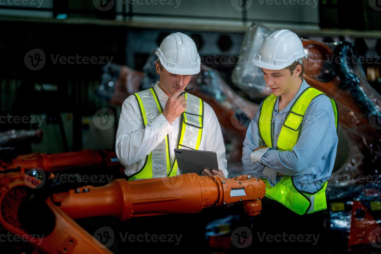 företag ingenjörer möte och kontroll ny maskin robot. arbetare gående på lager industri svetsning maskin. företag förhandling begrepp och teknologi. kvinnor använder sig av smart läsplatta till närvarande man. foto