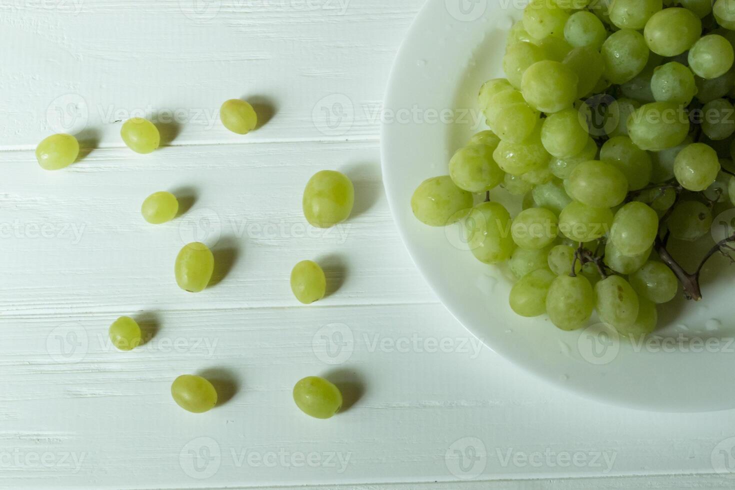 mogen vindruvor i en tallrik på en vit trä- tabell. topp se. foto