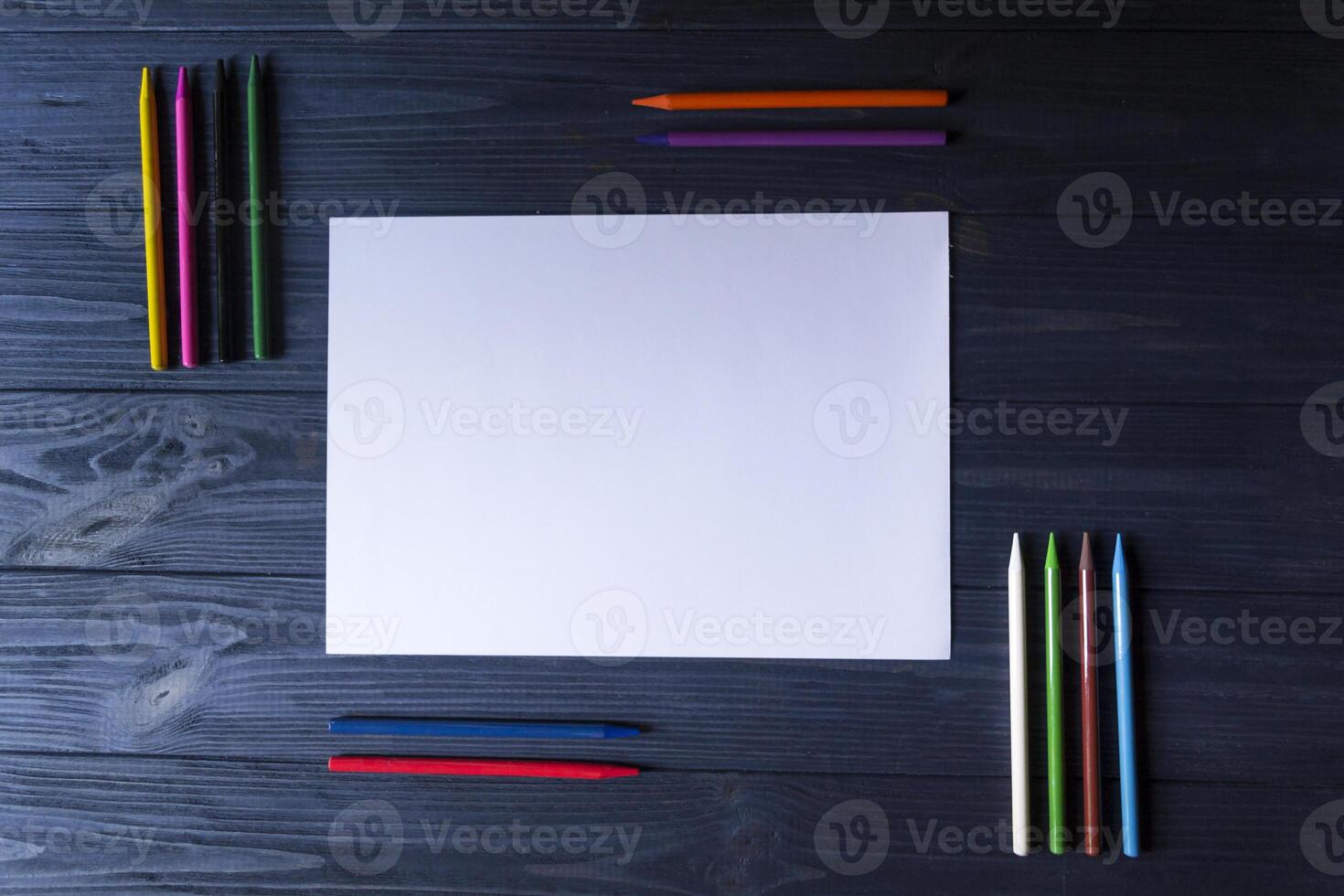 palett av flerfärgad pennor och de ark av vit papper på mörk blå trä- skrivbord. foto