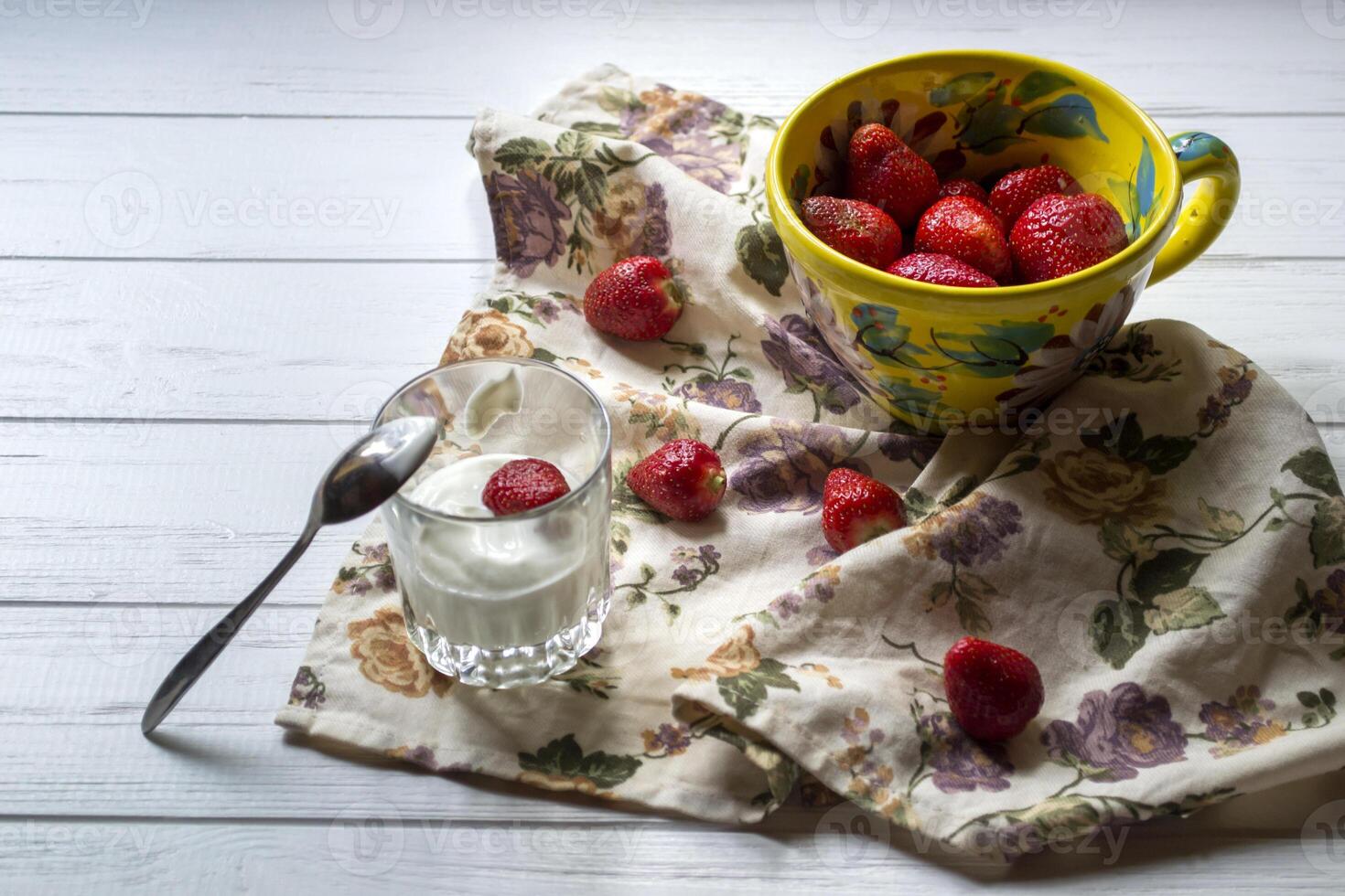 en råna av mogen jordgubbar och glas av grädde på en vit trä- tabell. de friska mat. foto