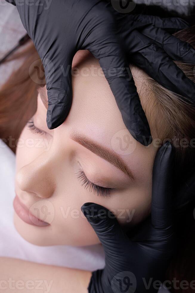 närbild demonstration av permanent smink efter ögonbryn design procedur. pmu procedur, permanent ögonbryn smink. foto