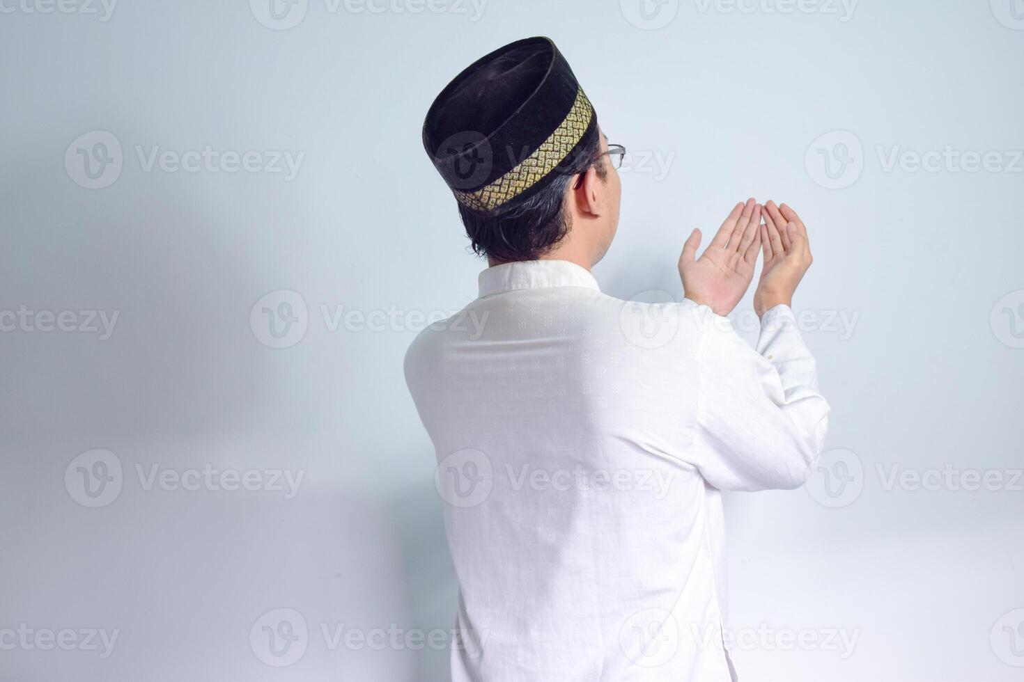 asiatisk muslim man bär glasögon och vit trasa bön- tillbaka sida utgör för Ramadhan och eid al fitr. isolerat vit bakgrund foto
