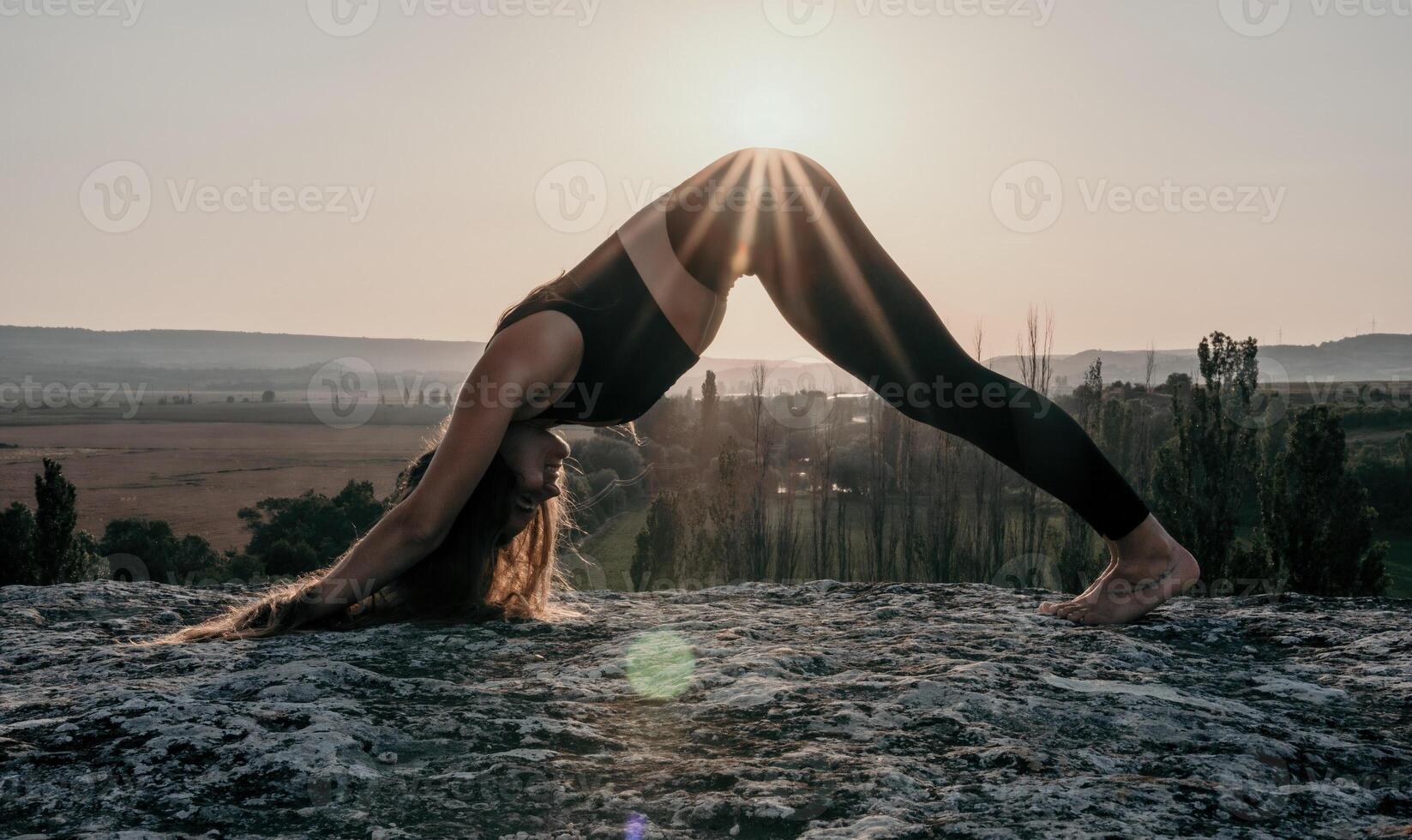 kondition kvinna. väl ser mitten åldrig kvinna med lång hår, kondition instruktör i damasker och blast håller på med stretching och pilates på de sten nära skog. kvinna kondition yoga rutin- begrepp. foto