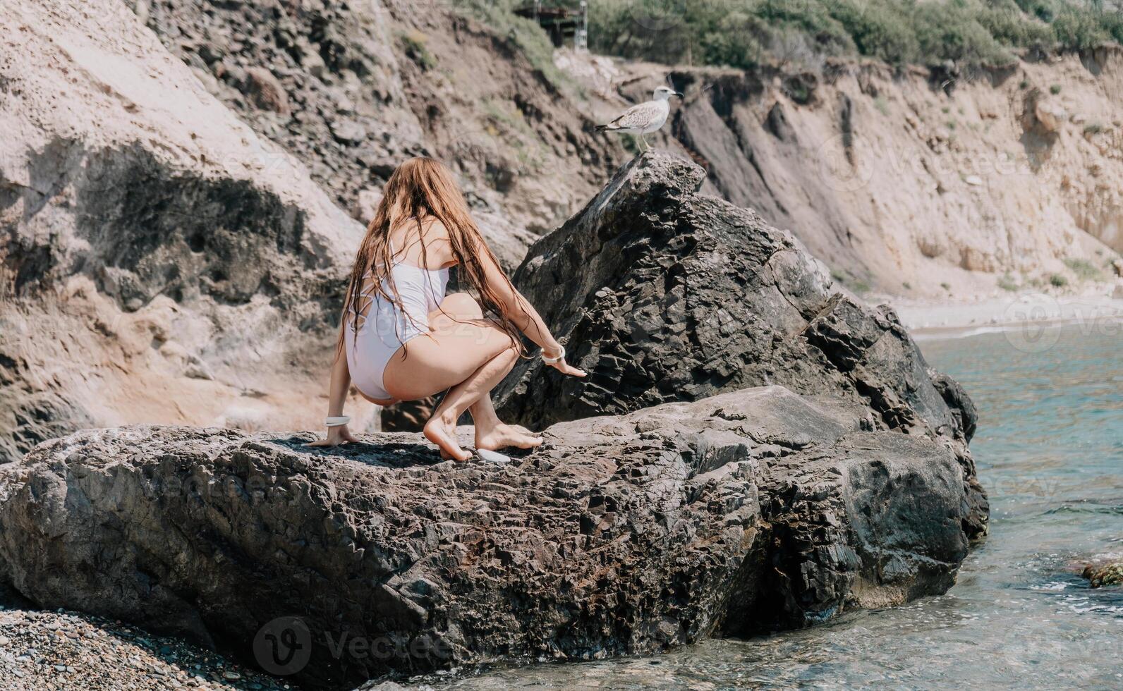 kvinna resa hav. Lycklig turist i vit bikini njut av tar bild utomhus för minnen. kvinna resande Framställ på de strand på hav omgiven förbi vulkanisk berg, delning resa äventyr resa foto