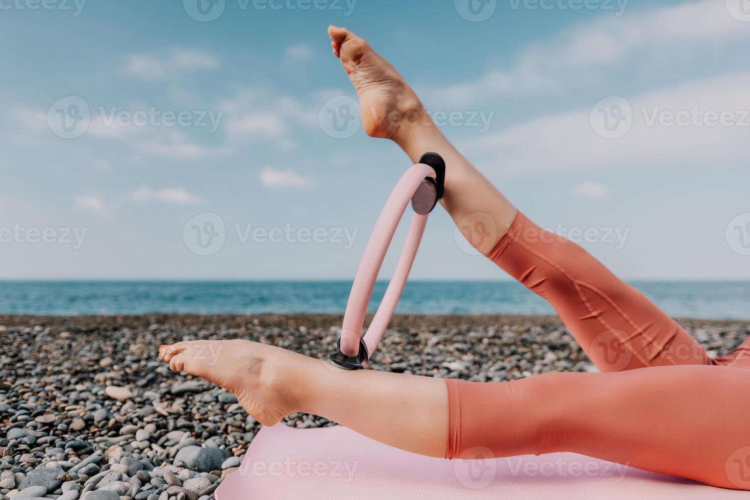 kvinna hav pilates. sportig Lycklig mitten åldrig kvinna praktiserande kondition på strand nära hav, leende aktiva kvinna Träning med ringa på yoga matta utanför, njuter friska livsstil, harmoni och meditation foto