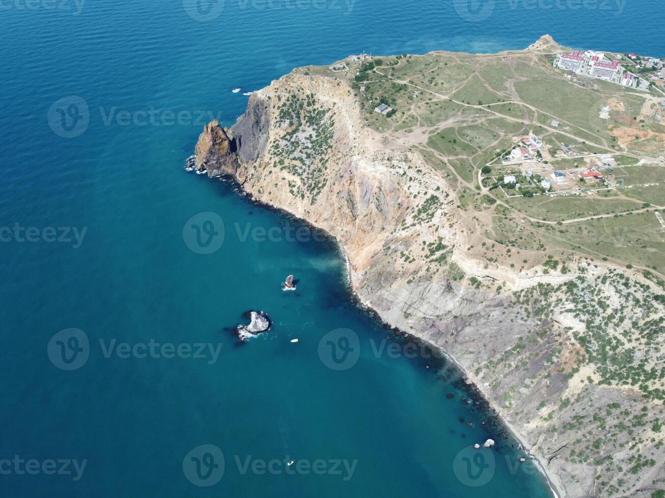 antenn se från ovan på lugna azurblå hav och vulkanisk klippig stränder. små vågor på vatten yta i rörelse fläck. natur sommar hav hav strand bakgrund. ingen. Semester, semester och resa begrepp foto