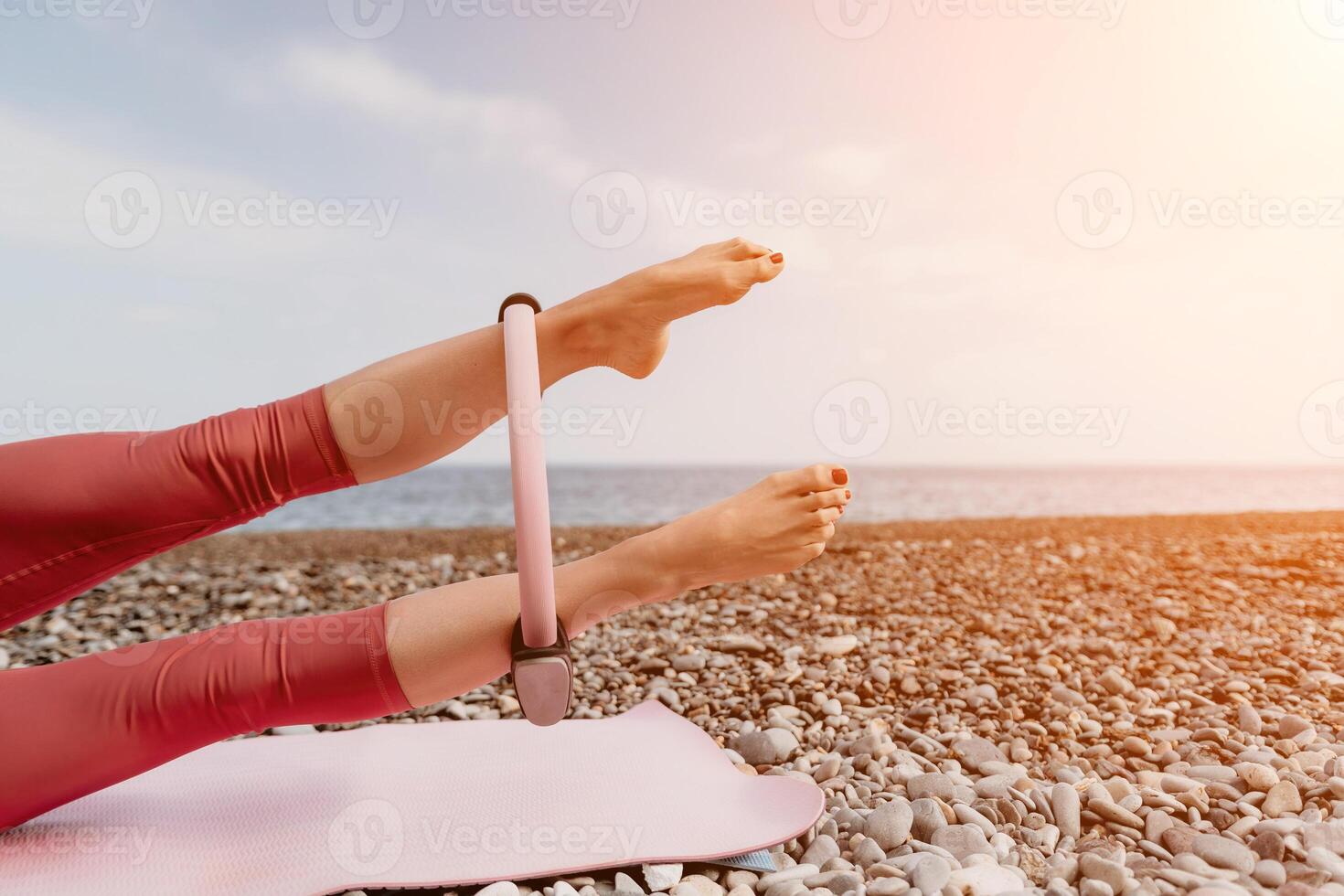 kvinna hav pilates. sportig Lycklig mitten åldrig kvinna praktiserande kondition på strand nära hav, leende aktiva kvinna Träning med ringa på yoga matta utanför, njuter friska livsstil, harmoni och meditation foto