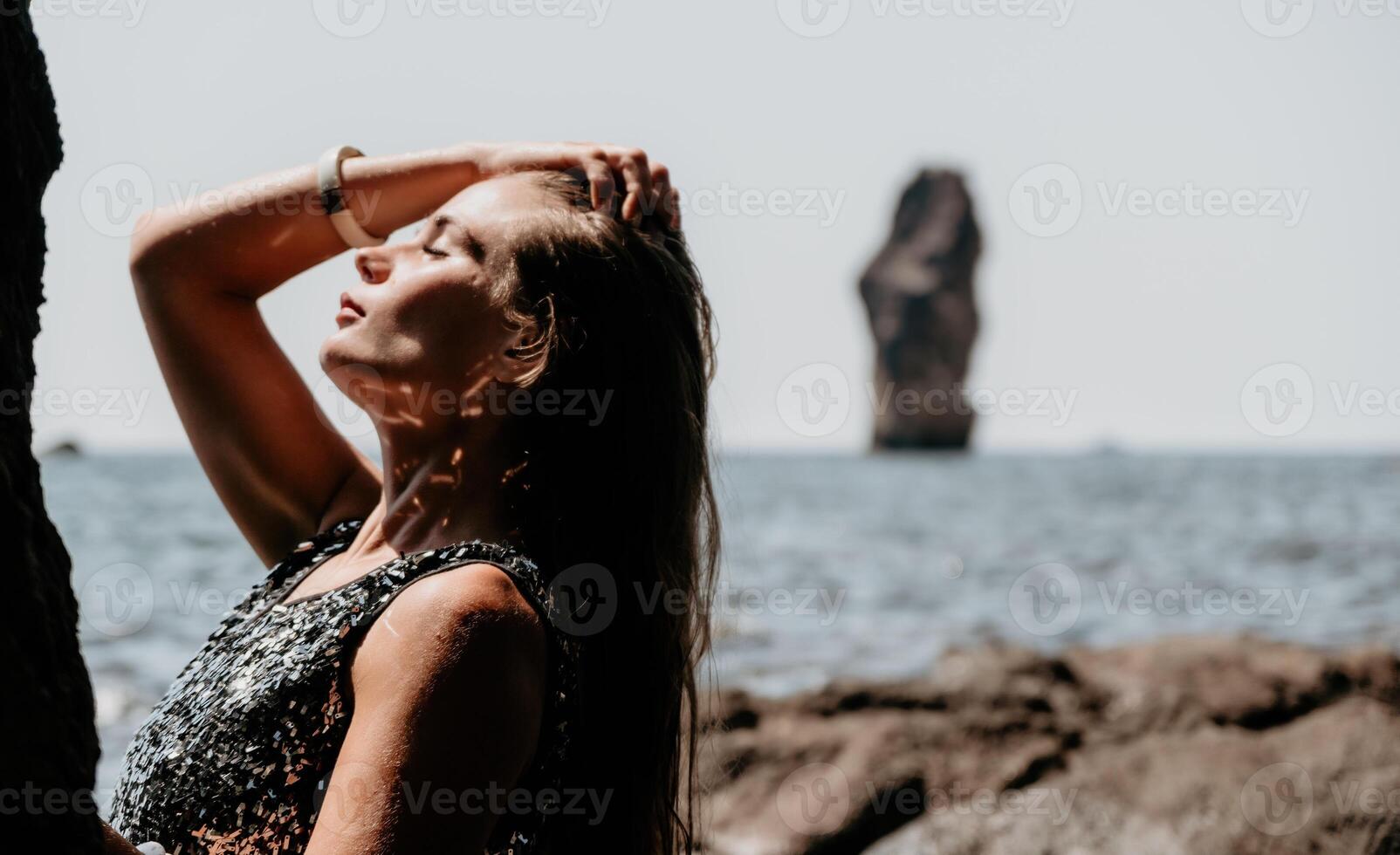 kvinna sommar resa hav. Lycklig turist njut av tar bild utomhus för minnen. kvinna resande Framställ på de strand på hav omgiven förbi vulkanisk berg, delning resa äventyr resa foto