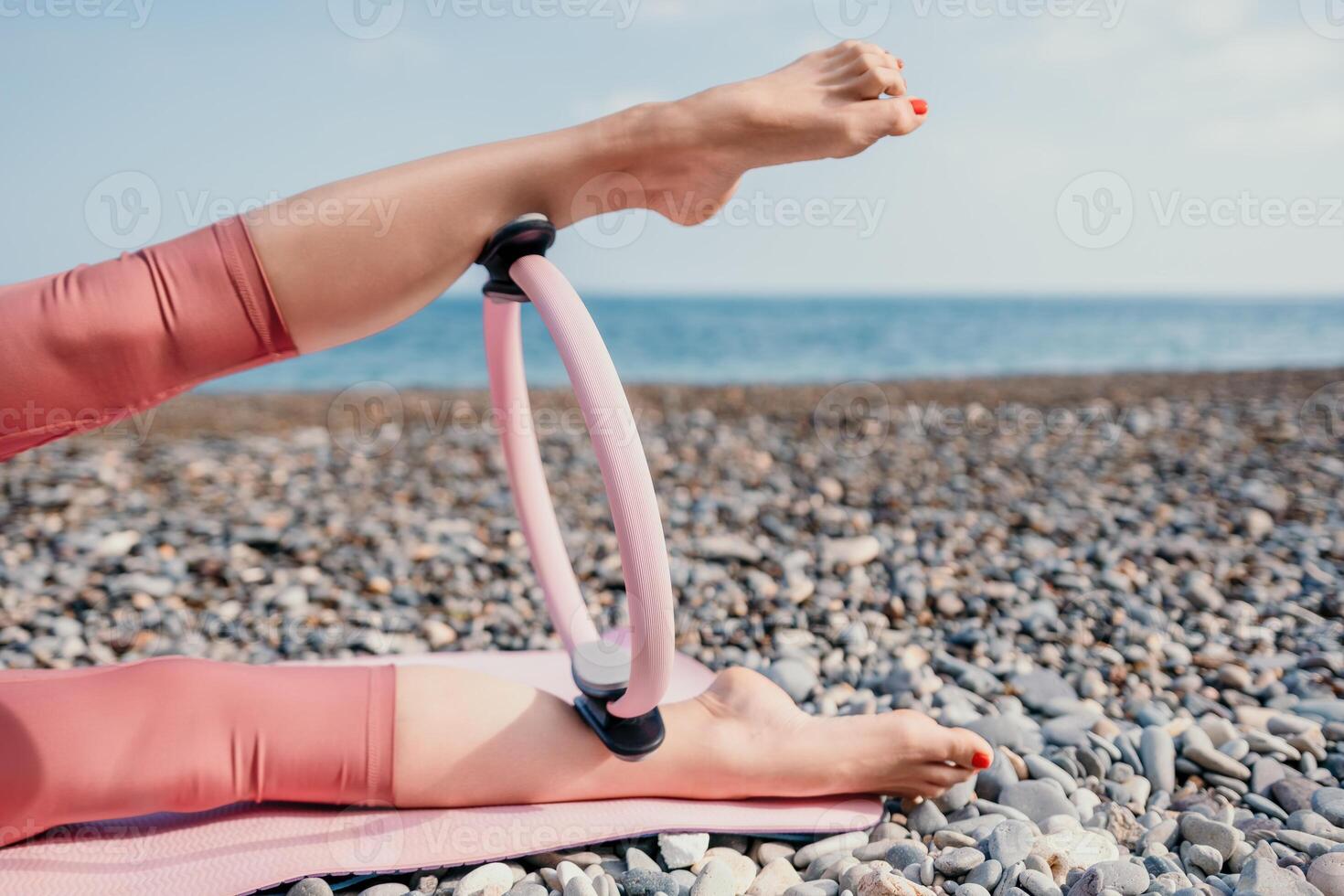 kvinna hav pilates. sportig Lycklig mitten åldrig kvinna praktiserande kondition på strand nära hav, leende aktiva kvinna Träning med ringa på yoga matta utanför, njuter friska livsstil, harmoni och meditation foto