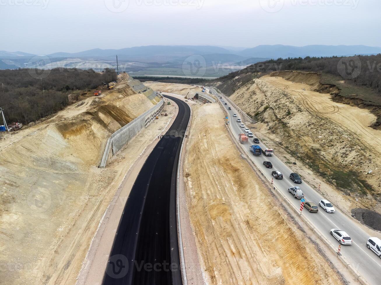 berg väg sammandragning. arbetare förstärka de backe över de ny väg. väg konstruktion i framsteg på backe natur kanjon. infrastruktur utveckling och logistik. antenn Drönare skott foto