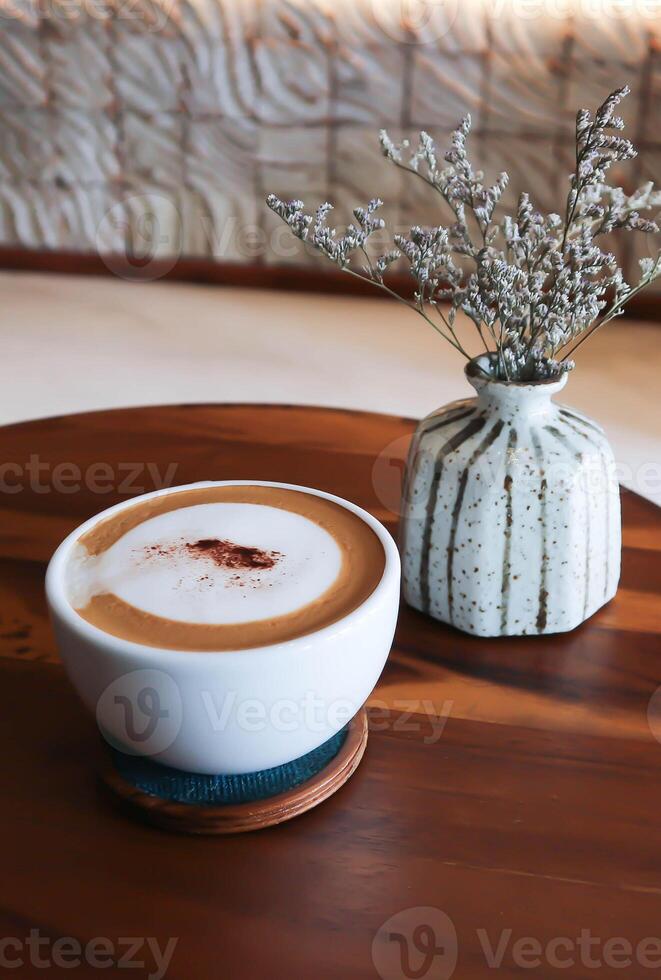 varm kaffe, cappuccino kaffe eller latte kaffe eller platt vit eller mocka kaffe och caspia blomma i en vas foto