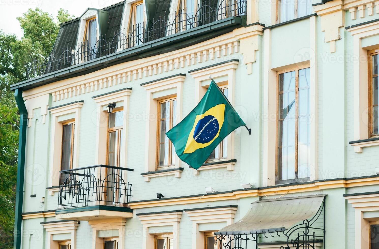 de grön flagga av de Land av Brasilien fladdrar i de vind mot de gul vägg av de hus. foto