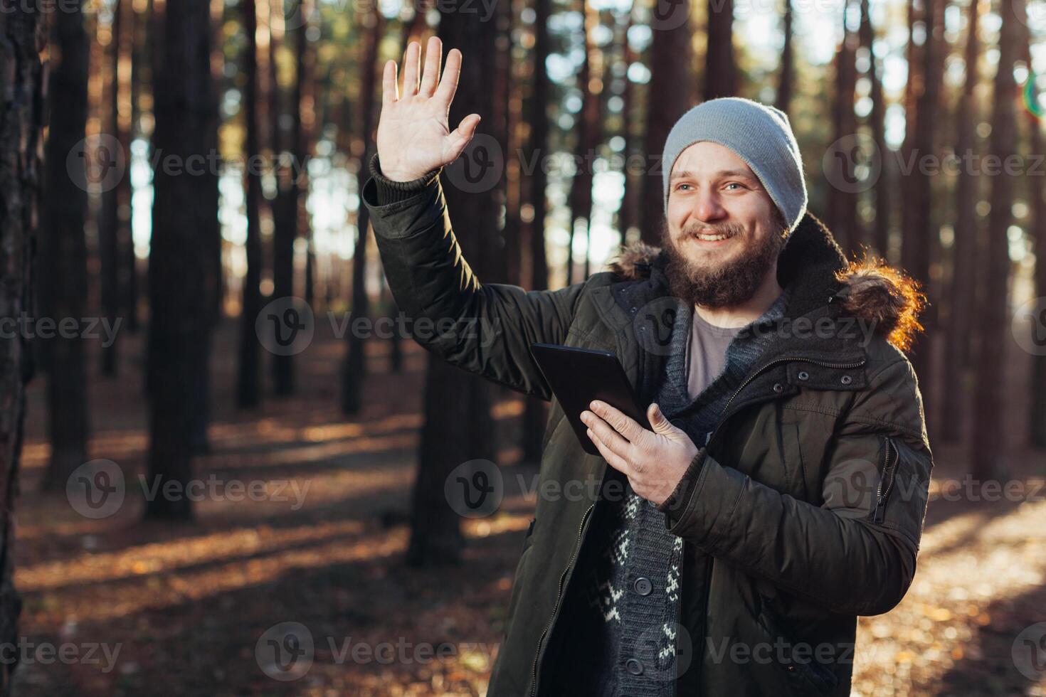 stänga upp porträtt av vuxen manlig vandrare använder sig av digital flik och ser för plats under vandra i natur. man på vandra använder sig av digital läsplatta för navigering. foto