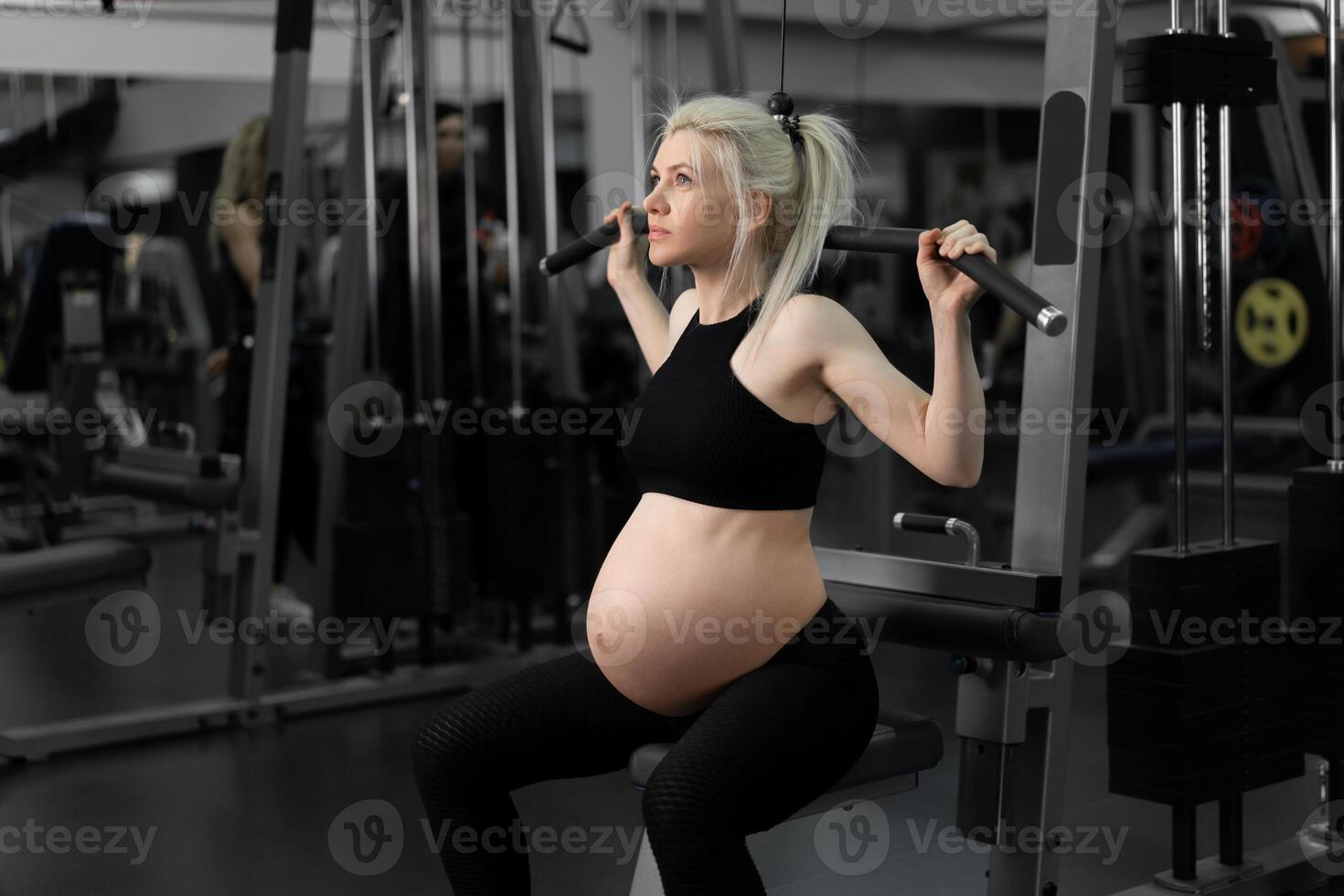 Gym träna gravid kvinna sportkläder Träning axlar med övning maskin foto