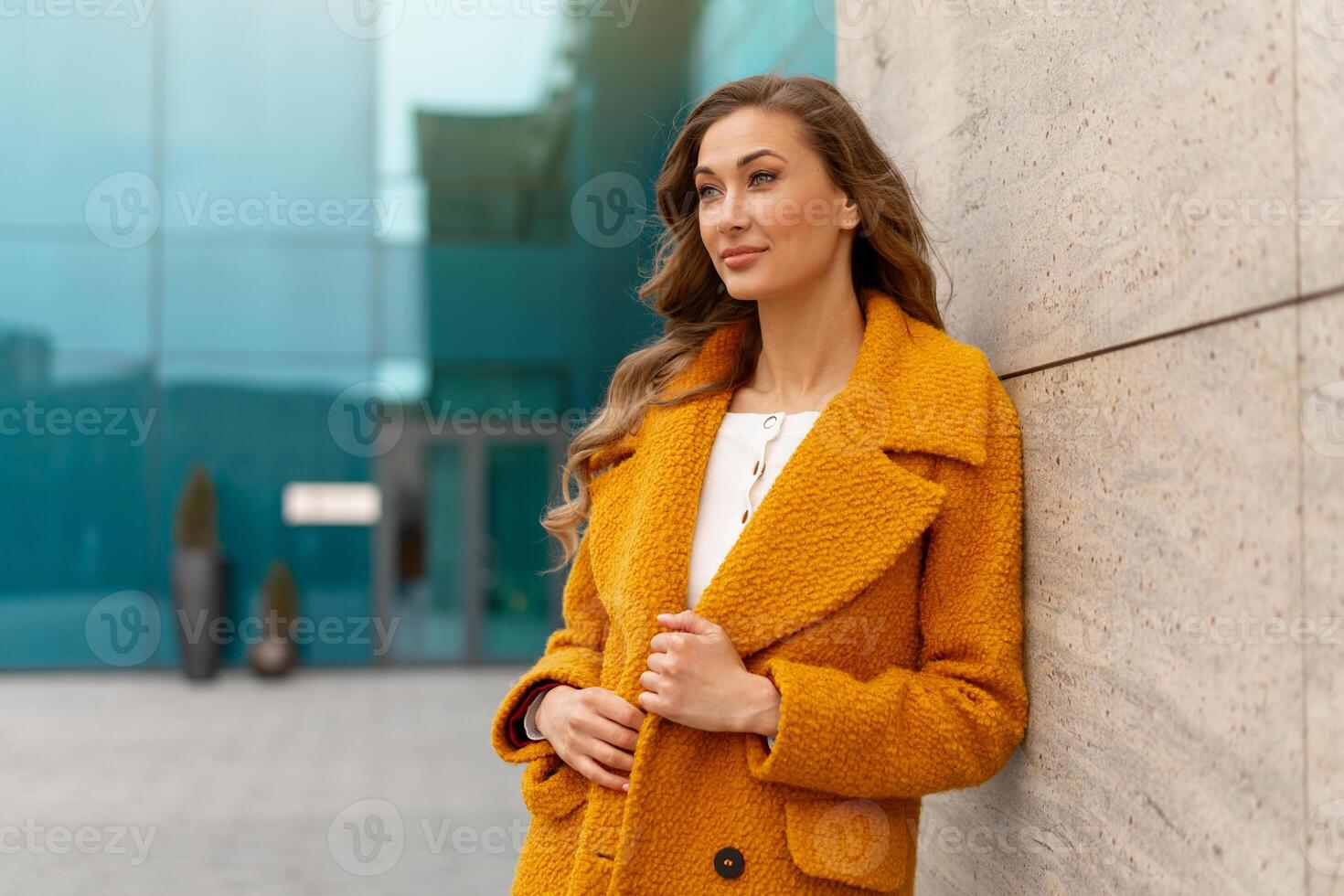 företag kvinna klädd gul täcka stående utomhus korporativ byggnad bakgrund foto