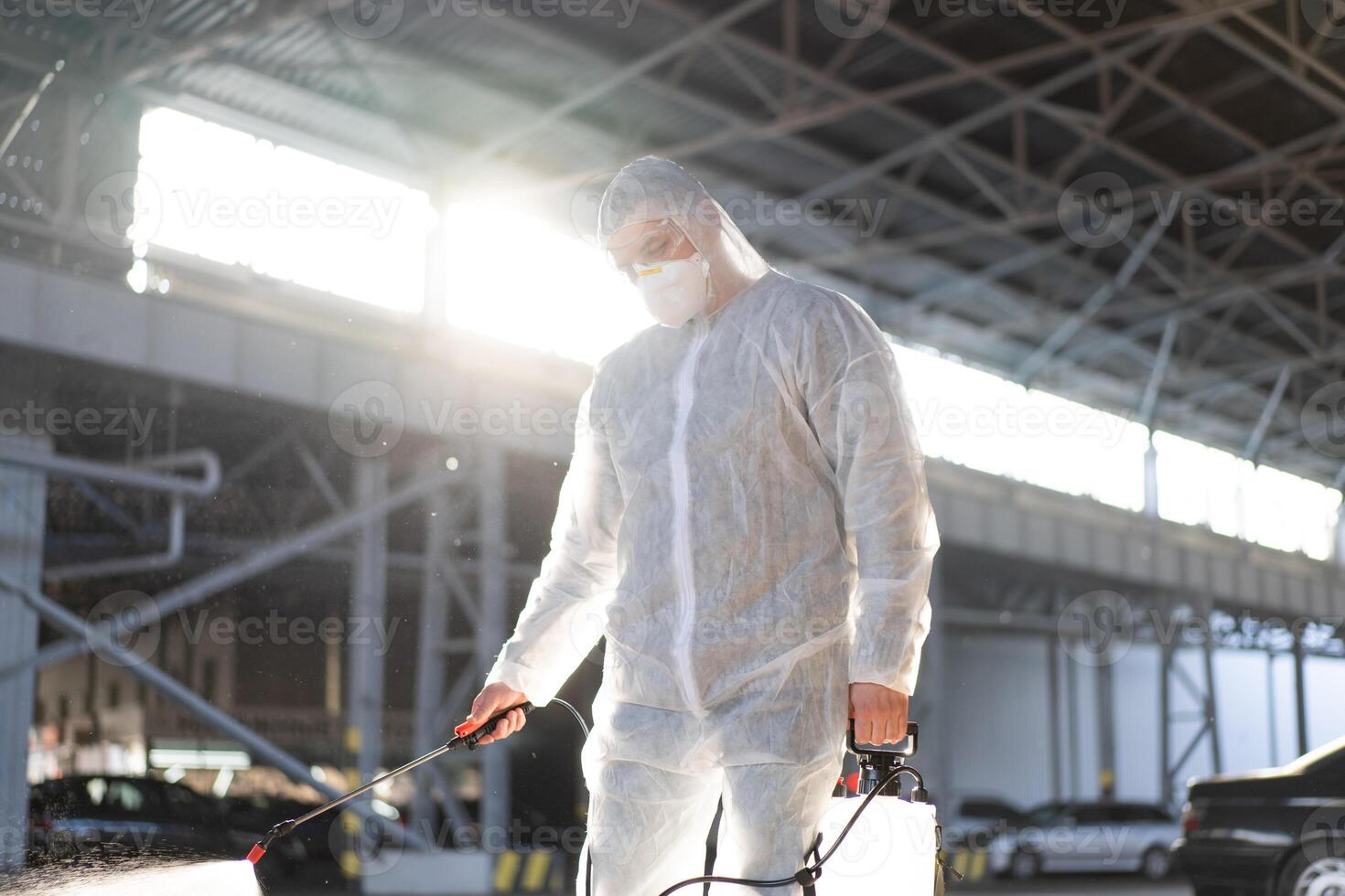 man klädd vit skyddande overall besprutning yta antibakteriell desinfektionsmedel spruta under karantän foto